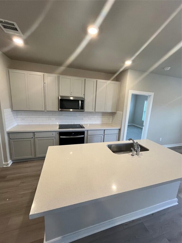 264 Little Green Trl, Jarrell, TX 76537 - kitchen with stainless steel microwave, tasteful backsplash, light countertops, dark wood finished floors, and oven