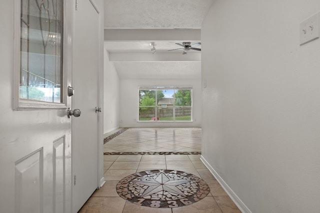 hall with light tile patterned floors, baseboards, vaulted ceiling, and inlaid floor details