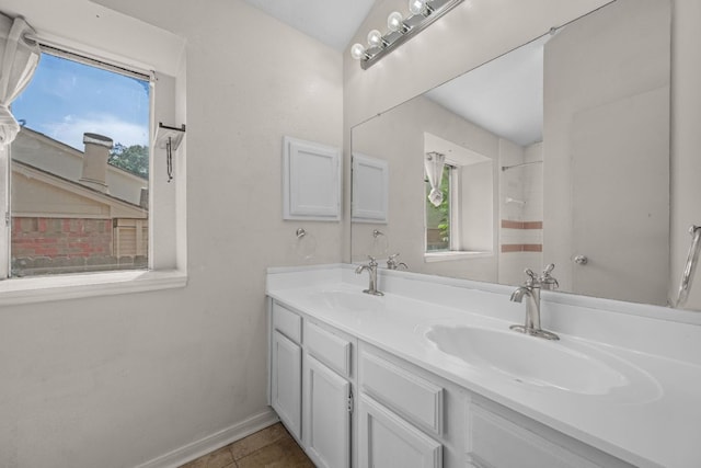 full bath featuring plenty of natural light, double vanity, tile patterned floors, and baseboards