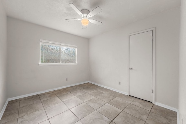 spare room featuring a ceiling fan, light tile patterned floors, and baseboards