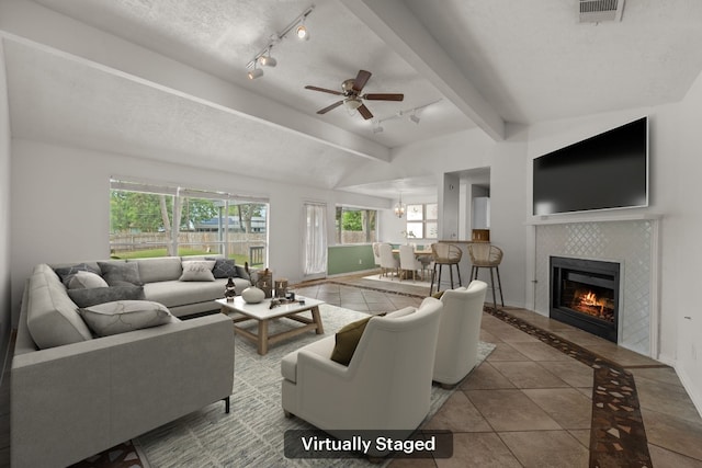 living room featuring track lighting, tile patterned floors, a tiled fireplace, ceiling fan, and baseboards