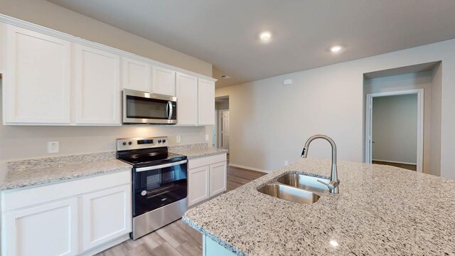2402 Bee Creek Dr, Copperas Cove, TX 76522 - kitchen with appliances with stainless steel finishes, a sink, light wood-style flooring, and white cabinets