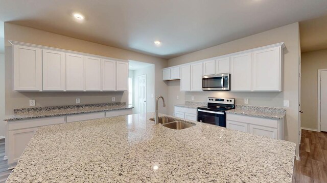 2402 Bee Creek Dr, Copperas Cove, TX 76522 - kitchen featuring electric range oven, stainless steel microwave, a sink, white cabinets, and wood finished floors