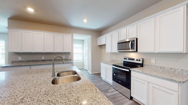 2402 Bee Creek Dr, Copperas Cove, TX 76522 - kitchen with appliances with stainless steel finishes, a sink, white cabinets, recessed lighting, and light wood-style floors