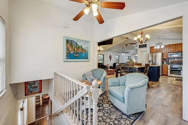 living room with a chandelier, vaulted ceiling, ceiling fan, plenty of natural light, and light wood-type flooring