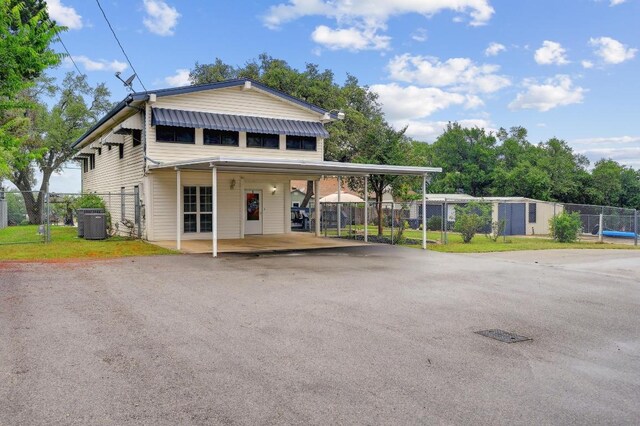 view of front of property featuring driveway, fence, central air condition unit, a gate, and a carport