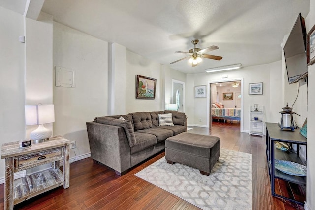 living room featuring ceiling fan, dark wood-style floors, and baseboards