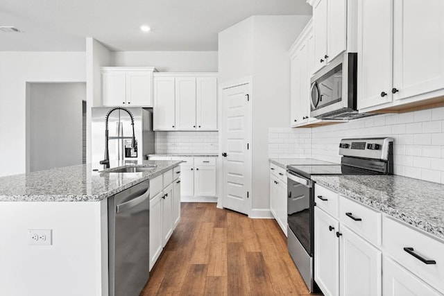 9321 Gladsome Path, Manor, TX 78653 - kitchen featuring appliances with stainless steel finishes, a sink, wood finished floors, white cabinetry, and recessed lighting