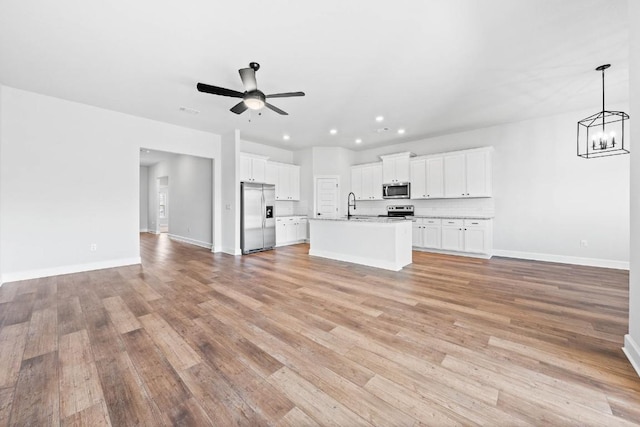 9321 Gladsome Path, Manor, TX 78653 - unfurnished living room featuring a ceiling fan, light wood finished floors, baseboards, a chandelier, and recessed lighting