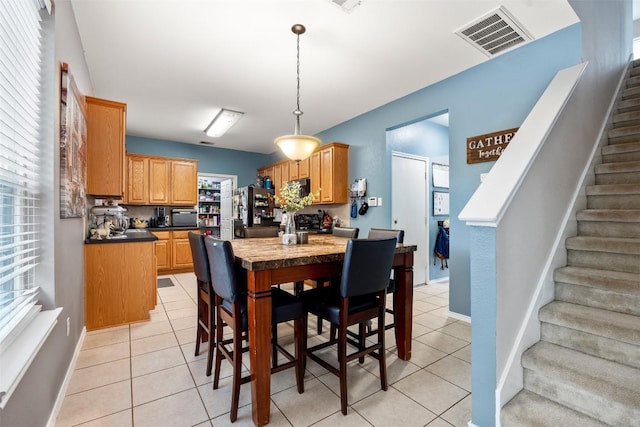 dining room with stairs, light tile patterned floors, and baseboards