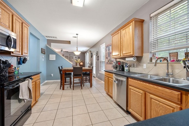kitchen featuring appliances with stainless steel finishes, a sink, decorative backsplash, and dark countertops