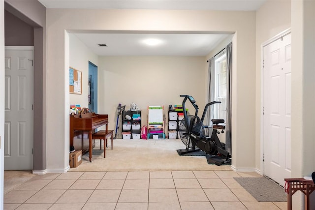 workout area featuring light carpet, light tile patterned floors, and baseboards