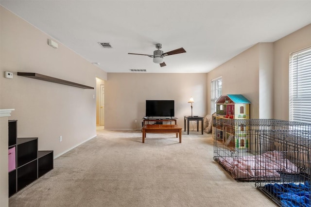 living area with ceiling fan, light colored carpet, and baseboards