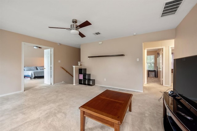 unfurnished living room with light colored carpet, a ceiling fan, and baseboards