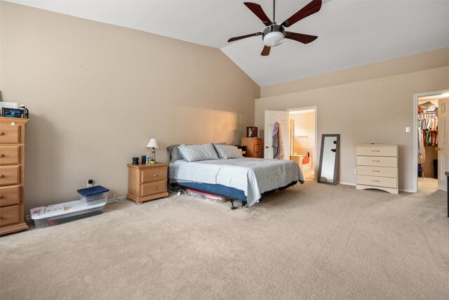 bedroom with light carpet, a spacious closet, a closet, ensuite bathroom, and a ceiling fan