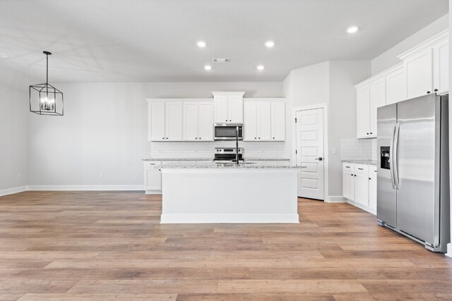 9701 Gladsome Path, Manor, TX 78653 - kitchen with appliances with stainless steel finishes, decorative backsplash, an island with sink, a chandelier, and white cabinets