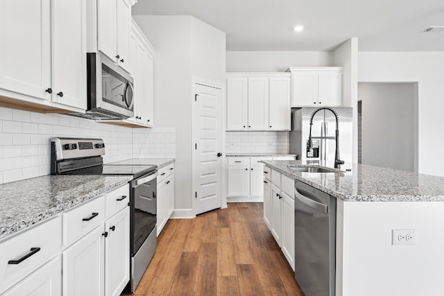 9701 Gladsome Path, Manor, TX 78653 - kitchen featuring appliances with stainless steel finishes, a sink, wood finished floors, a kitchen island with sink, and white cabinets