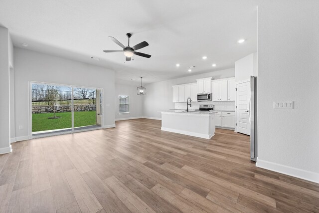 9701 Gladsome Path, Manor, TX 78653 - unfurnished living room with a sink, recessed lighting, ceiling fan, light wood-style floors, and baseboards