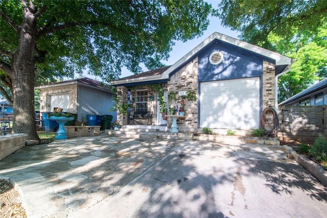 view of front of house featuring fence, driveway, brick siding, and an attached garage