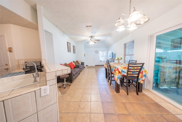 dining area featuring ceiling fan, a textured ceiling, a chandelier, and light tile patterned flooring