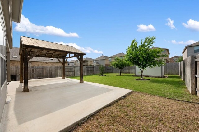 view of yard featuring a patio, an outdoor structure, a storage shed, and a residential view