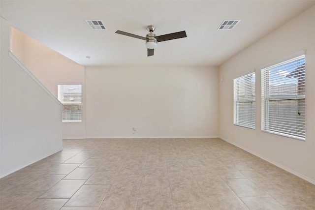 spare room featuring a ceiling fan, plenty of natural light, light tile patterned floors, and baseboards