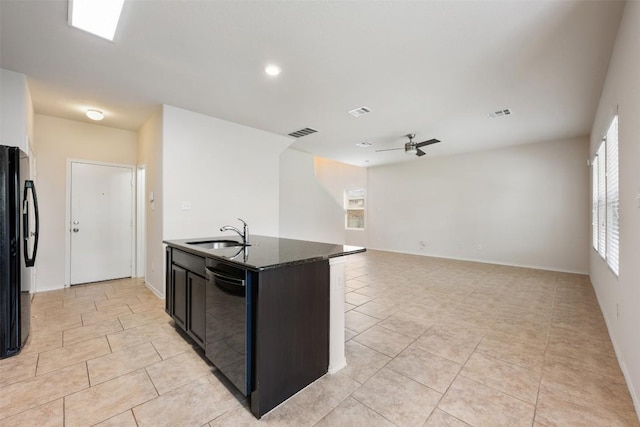 kitchen featuring a sink, black appliances, ceiling fan, light tile patterned floors, and dark stone counters