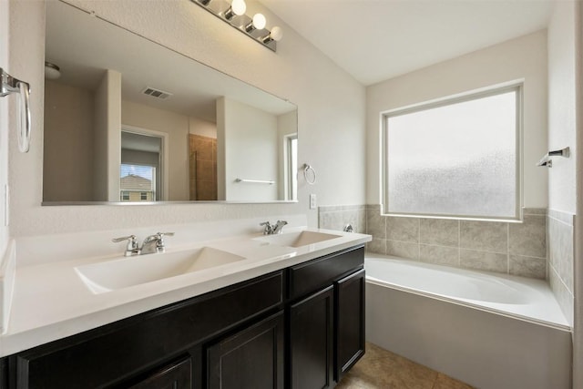 full bathroom with healthy amount of natural light, a bath, double vanity, and tile patterned flooring