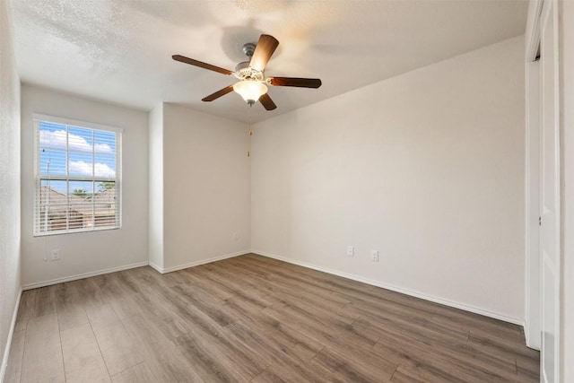 empty room featuring wood finished floors, ceiling fan, and baseboards