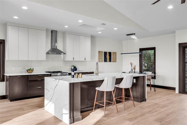 112 Paragon Ct, Lakeway, TX 78734 - kitchen with wall chimney range hood, modern cabinets, light wood finished floors, lofted ceiling, and recessed lighting