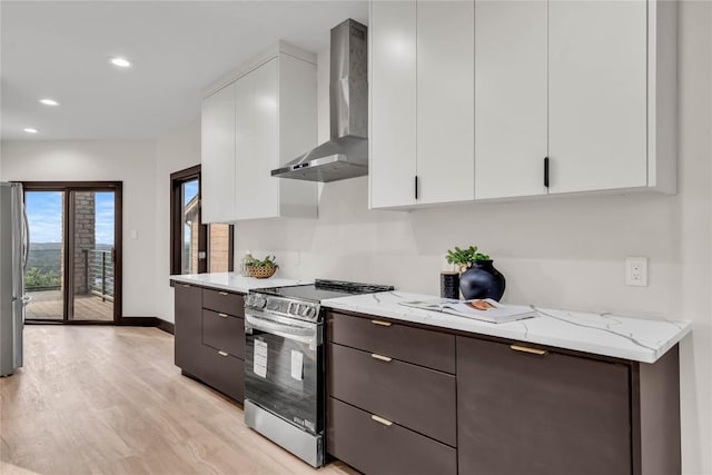 112 Paragon Ct, Lakeway, TX 78734 - kitchen with stainless steel appliances, wall chimney range hood, white cabinetry, light wood-style floors, and light stone counters