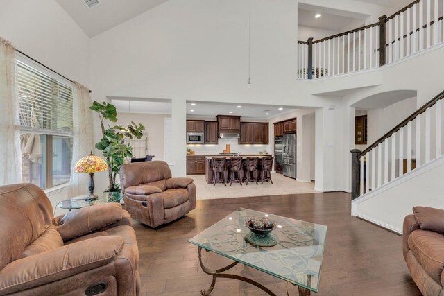 living room featuring high vaulted ceiling, wood finished floors, stairs, and baseboards