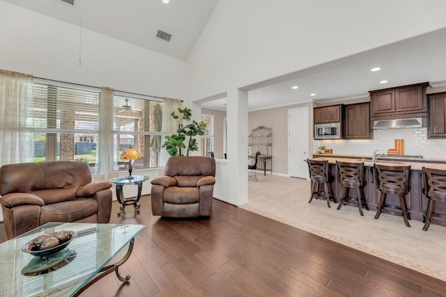 living area with hardwood / wood-style flooring, recessed lighting, baseboards, and high vaulted ceiling