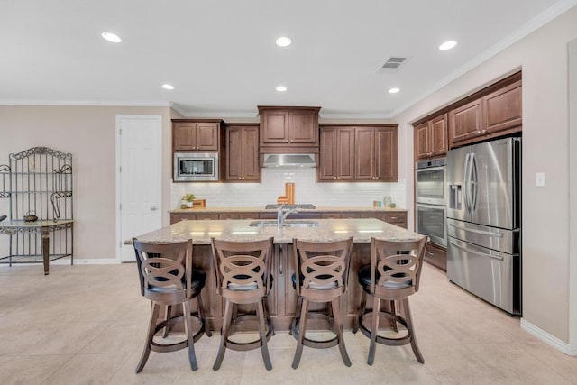 kitchen with stainless steel appliances, wall chimney exhaust hood, ornamental molding, a sink, and tasteful backsplash