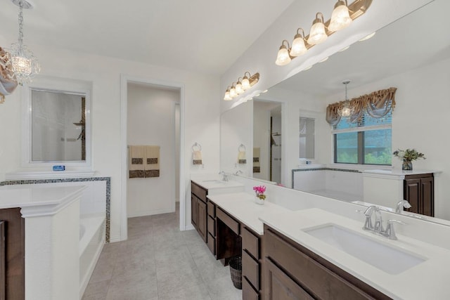 full bath featuring a chandelier, vanity, a bathtub, baseboards, and tile patterned floors