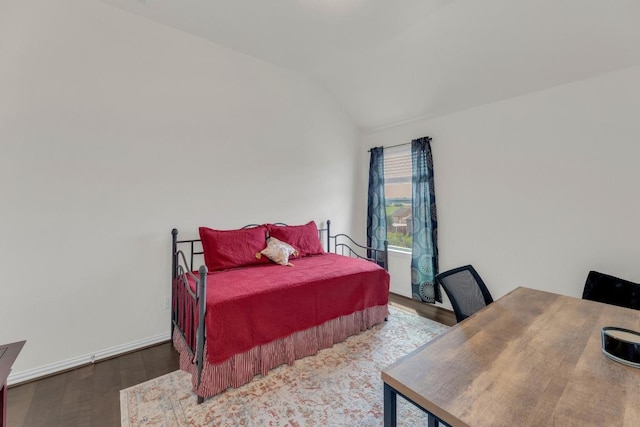 bedroom with wood finished floors and lofted ceiling
