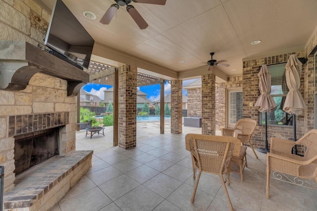 view of patio featuring an outdoor stone fireplace, a ceiling fan, and an outdoor pool