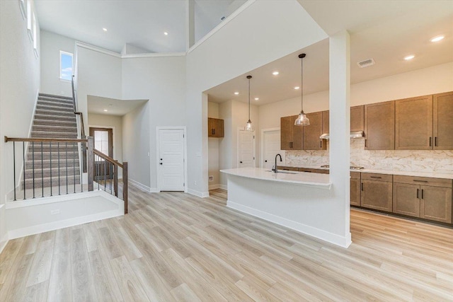 1401 S Brook Dr, Leander, TX 78641 - unfurnished living room with light wood-style flooring, stairway, a towering ceiling, and recessed lighting