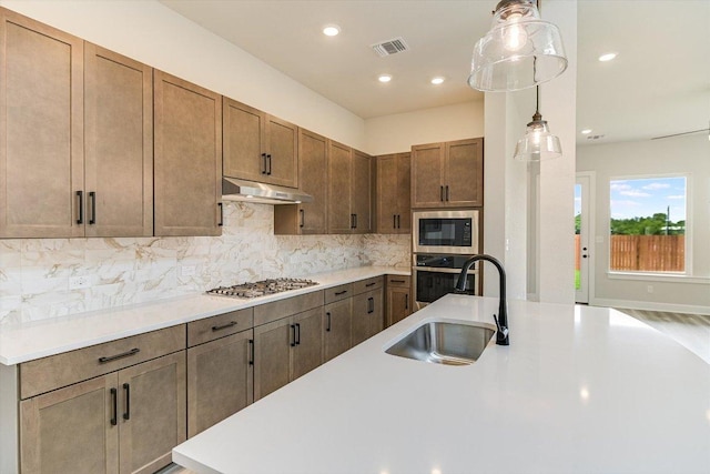 1401 S Brook Dr, Leander, TX 78641 - kitchen with stainless steel appliances, under cabinet range hood, light countertops, backsplash, and recessed lighting