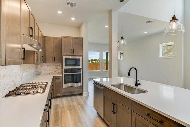 1401 S Brook Dr, Leander, TX 78641 - kitchen with stainless steel appliances, under cabinet range hood, light countertops, light wood-style floors, and tasteful backsplash