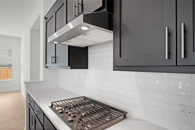 204 Ridgewell Loop, Georgetown, TX 78633 - kitchen featuring wall chimney exhaust hood, stainless steel gas cooktop, light countertops, tasteful backsplash, and baseboards