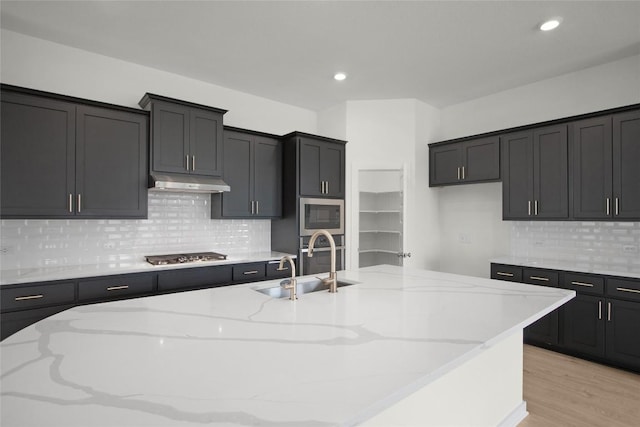 204 Ridgewell Loop, Georgetown, TX 78633 - kitchen featuring under cabinet range hood, appliances with stainless steel finishes, light stone counters, backsplash, and recessed lighting