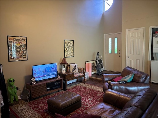 1404 Andra Ln, San Marcos, TX 78666 - living room featuring estacked washer and dryer, a towering ceiling, baseboards, and wood finished floors