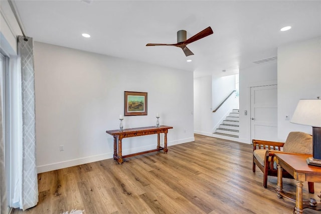 sitting room with stairs, ceiling fan, light wood-type flooring, baseboards, and recessed lighting
