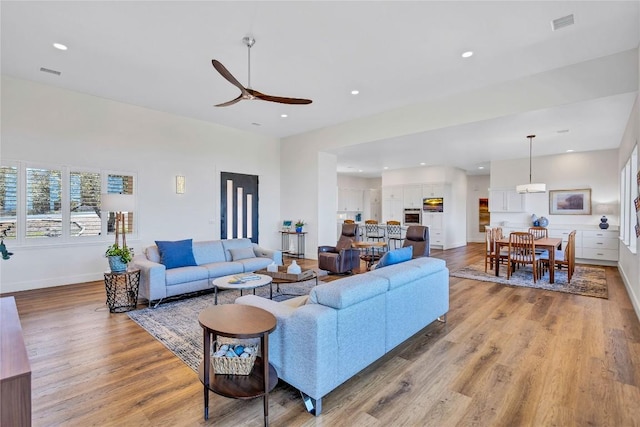 living area with ceiling fan, light wood-type flooring, recessed lighting, and baseboards