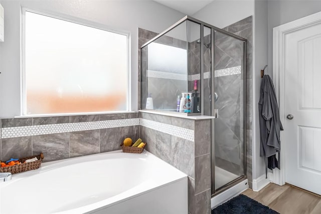 full bathroom with a shower stall, a bath, and wood finished floors