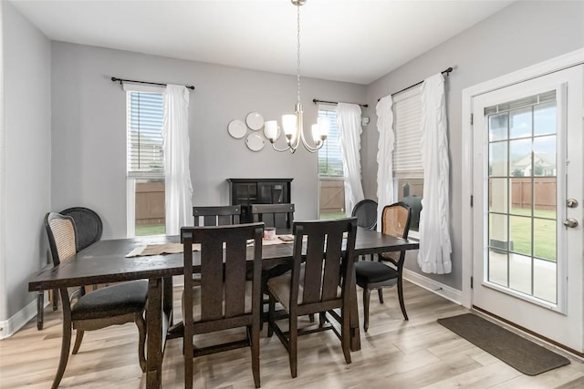 dining room featuring light wood-type flooring, a chandelier, plenty of natural light, and baseboards