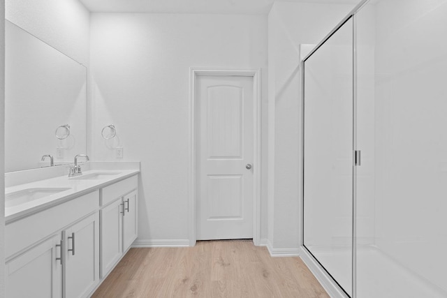 2416 Cattle Baron Trl, Leander, TX 78641 - full bathroom featuring wood finished floors, a shower stall, baseboards, and double vanity