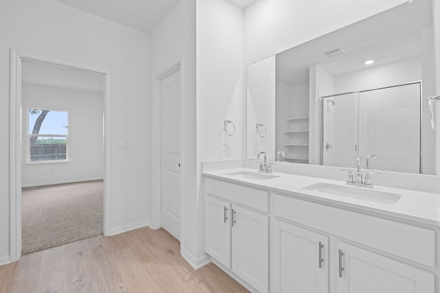 2416 Cattle Baron Trl, Leander, TX 78641 - full bathroom featuring wood finished floors, double vanity, a shower, and baseboards