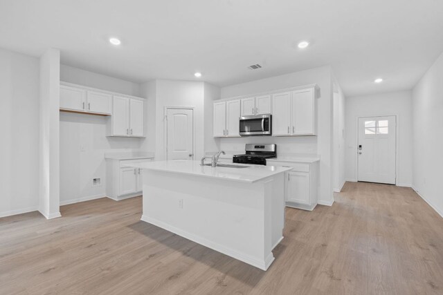 2416 Cattle Baron Trl, Leander, TX 78641 - kitchen featuring stainless steel appliances, a sink, white cabinets, light wood finished floors, and recessed lighting